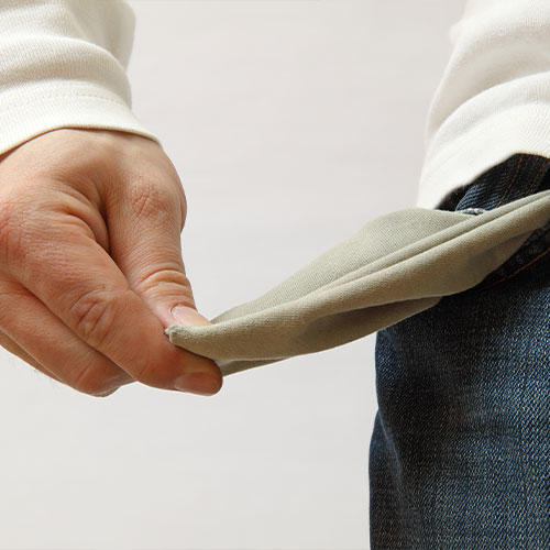 Ausschnitt einer Hand, die die Hoseninnentasche aus einer getragenen Jeans-Hose herauszieht.